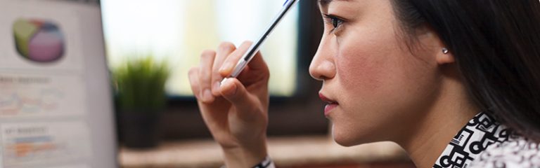 Lady looking at graphs scratching her head with a pen to think
